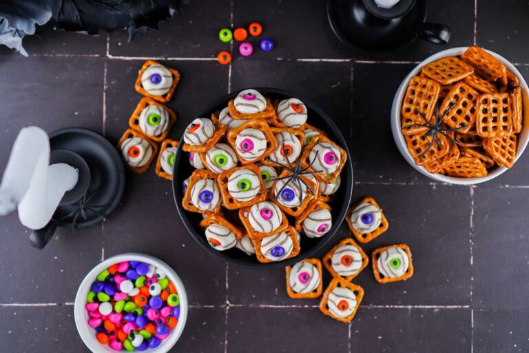 Halloween eyeball chocolate pretzel bites in bowls with colorful candy eyes.